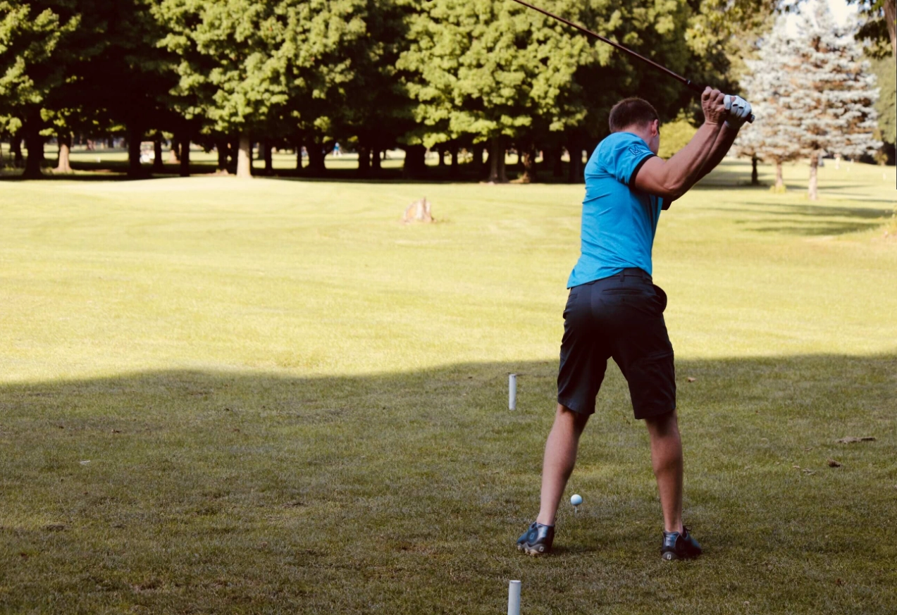 Man in blue, hitting his tee shot with a driver club